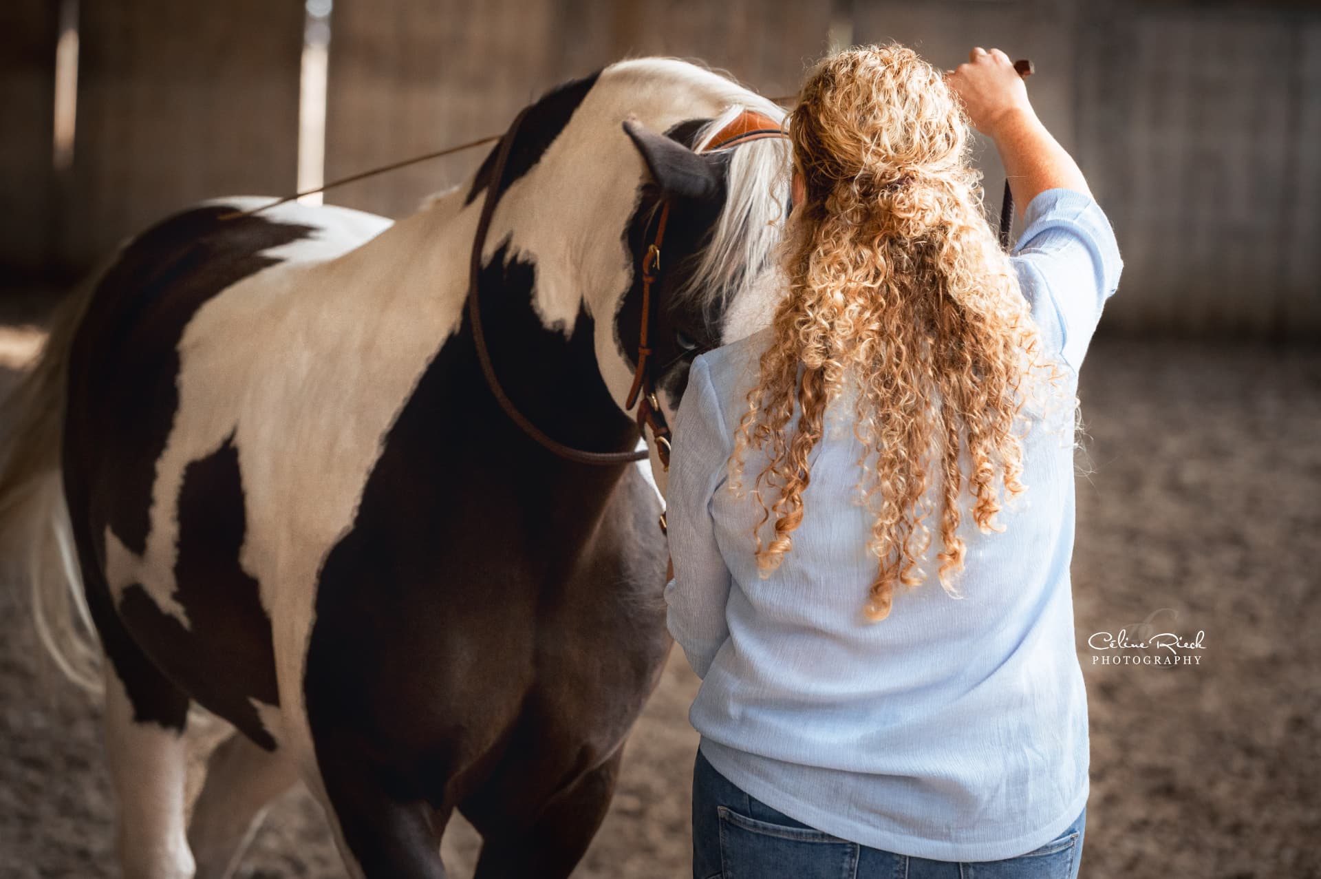 Heidi werkt met opgehefen teugel aan de hand met haar bonte paard in de binnenmanege
