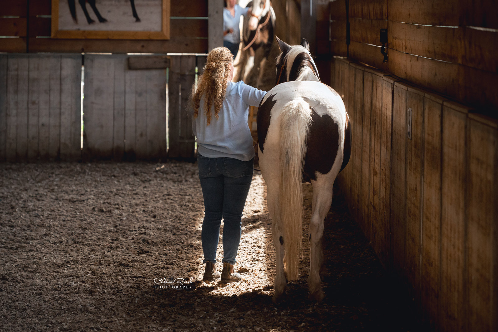 Heidi rust haar hand op de rug van haar bonte paard in de binnenmanege
