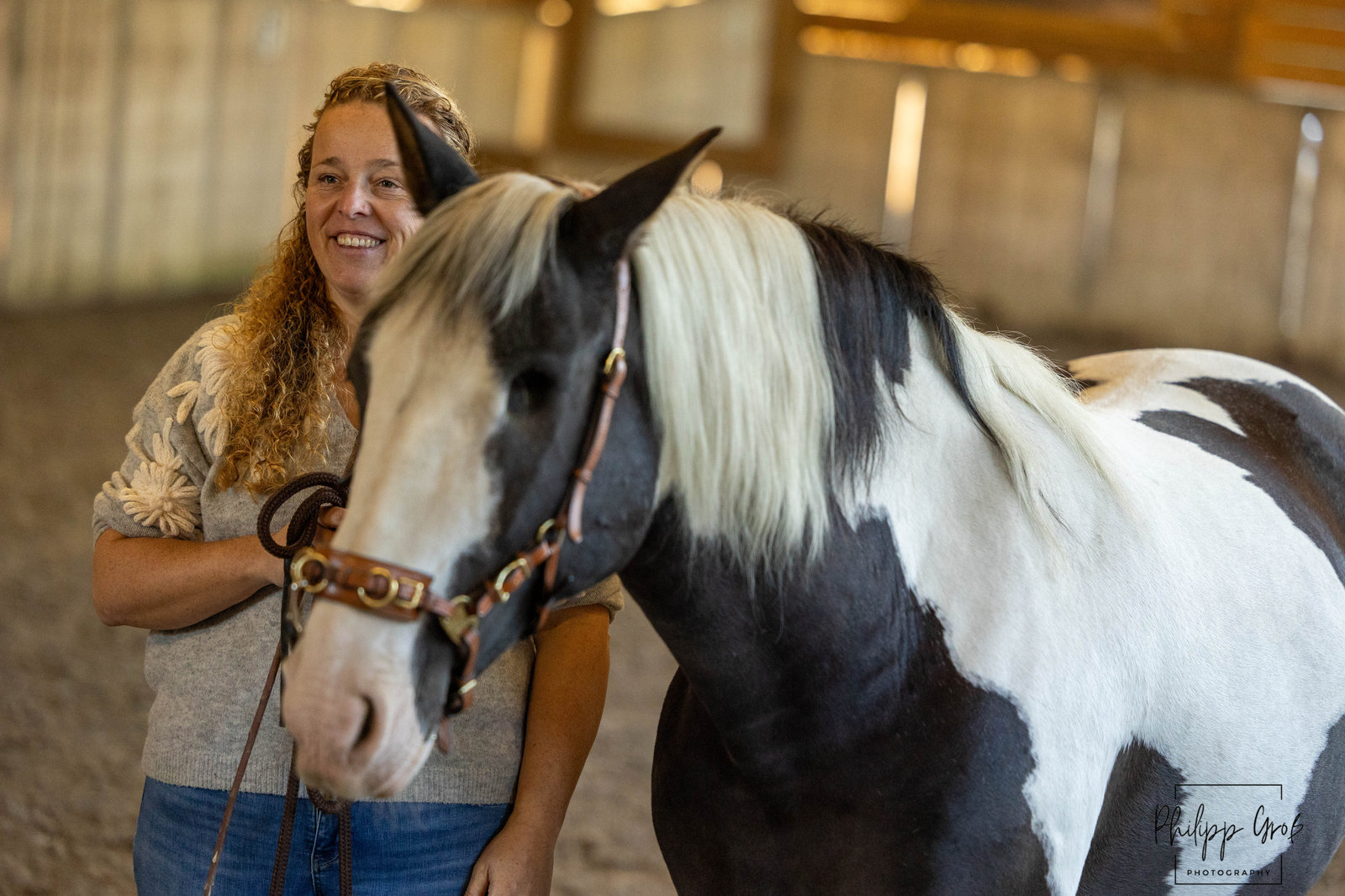 Heidi en haar zwart-wit bonte paard tijdens een grondwerksessie in de binnenmanege